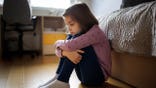 Little girl sitting alone on the floor at home