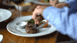Man cutting steak dinner at table