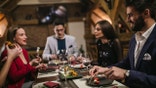 Young group of Friends dressed up having dinner while drinking wine in luxury restaurant