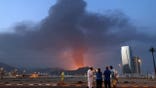 Foreign workers looking at tall plume of black smoke in Fujairah industrial zone