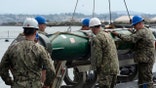 Sailors load a torpedo on ship.