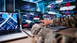 US servicemen in front of several screens.