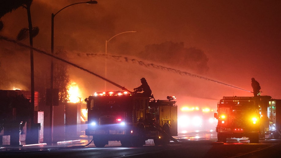 firefighters shoot water at fire from trucks