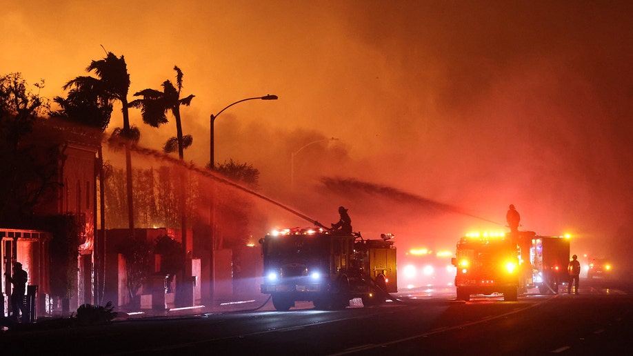 firefighters aim water hoses toward large fire
