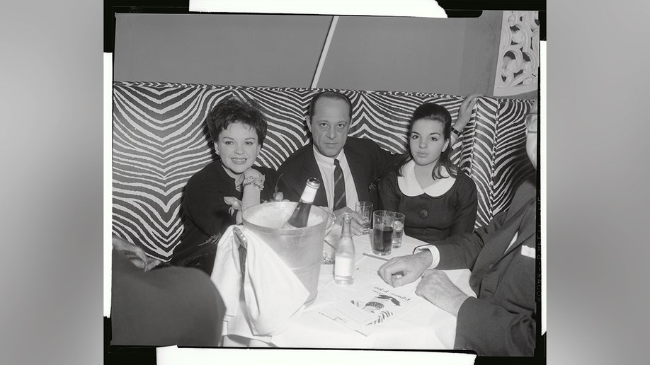 Judy Garland, Sid Luft, and Liza Minnelli sitting together at a table.