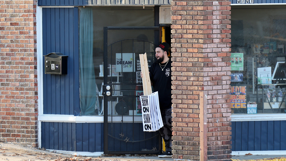 Man holding signs adjacent  to ceramic  wall