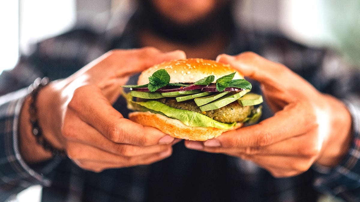 Man holding burger made of chickpea fritters