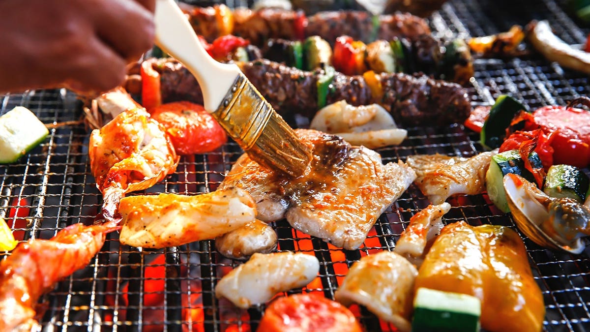 Man seasoning fish on grill grates