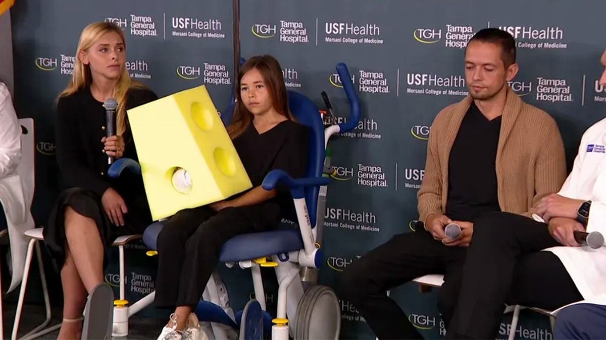 Leah está sentada con sus padres durante una rueda de prensa en el hospital.