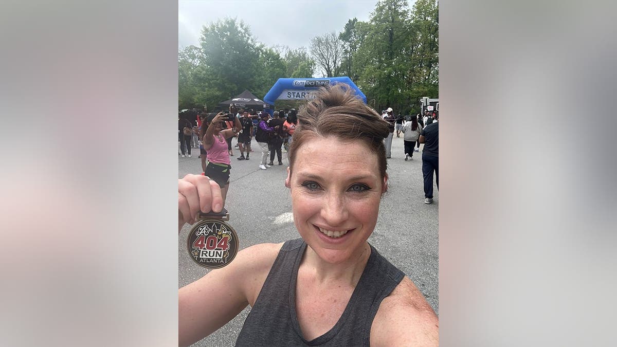 Lauren Bullis holding up a running medal