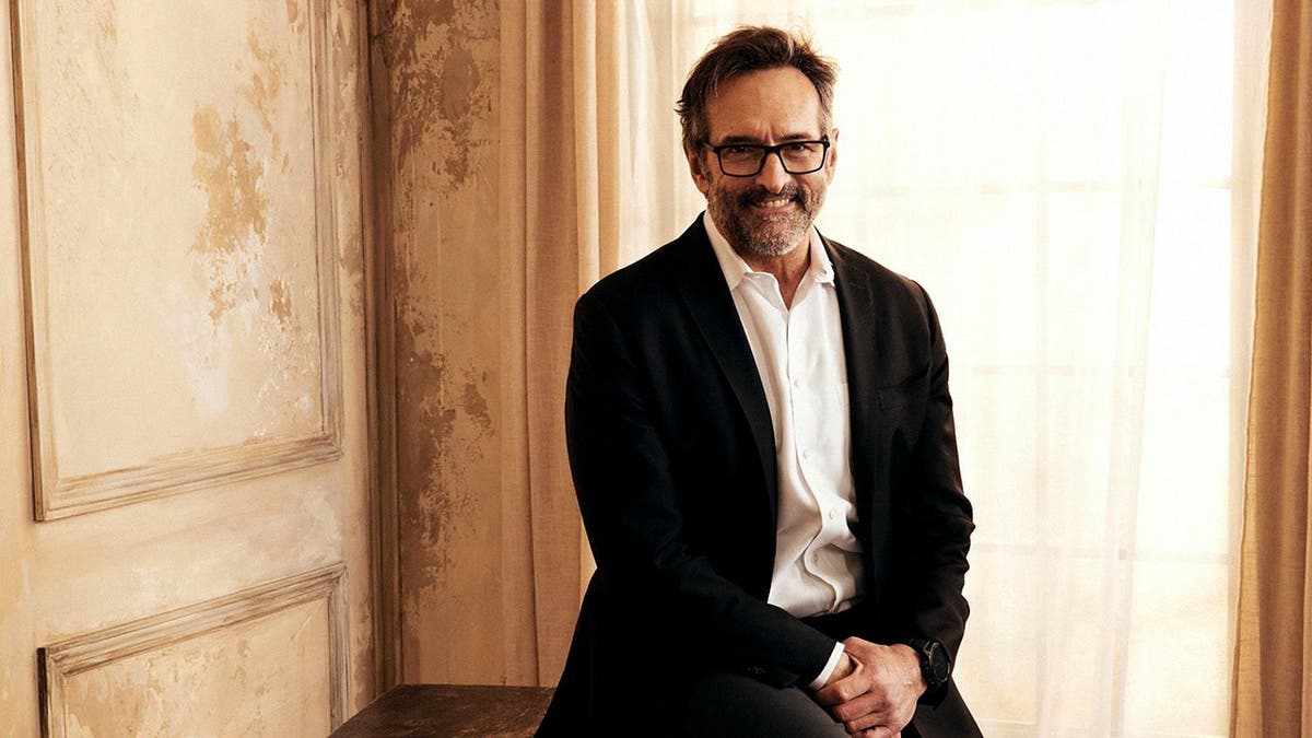 Roger D. Carstens posa para um retrato em frente a um fundo azul e branco