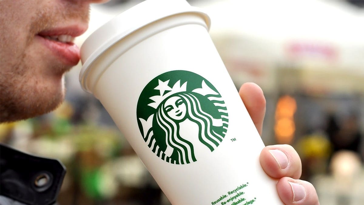 A man drinking Starbucks tea with a visible logo