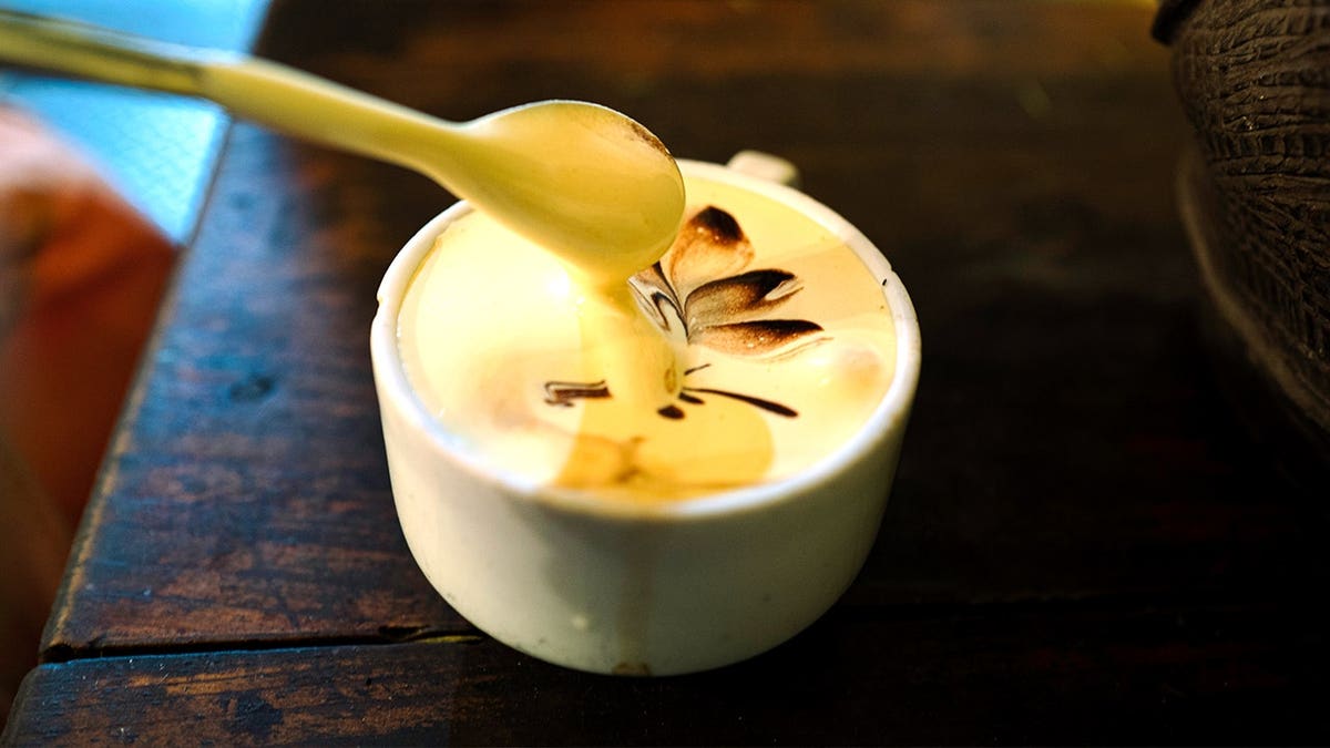 Person putting spoon in egg coffee drink