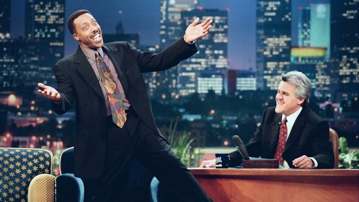 Comedian Arsenio Hall and Jay Leno seated during an interview on a television set