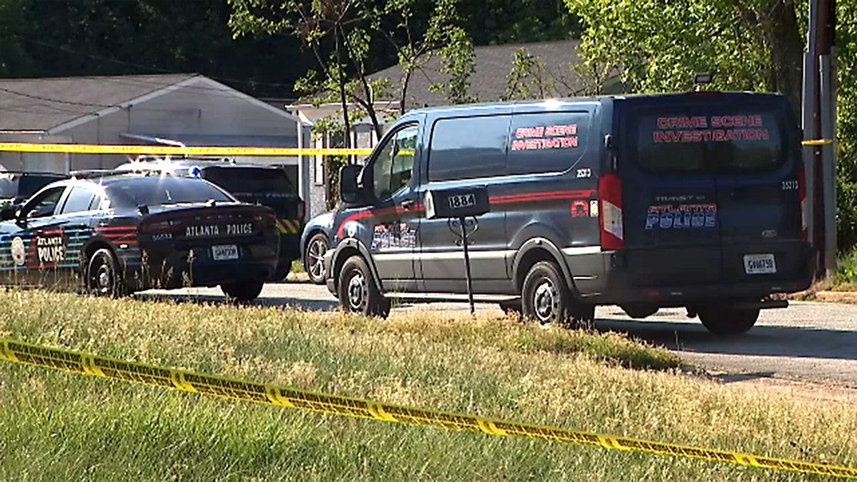 Atlanta Police vehicles are parked in a neighborhood behind yellow tape.