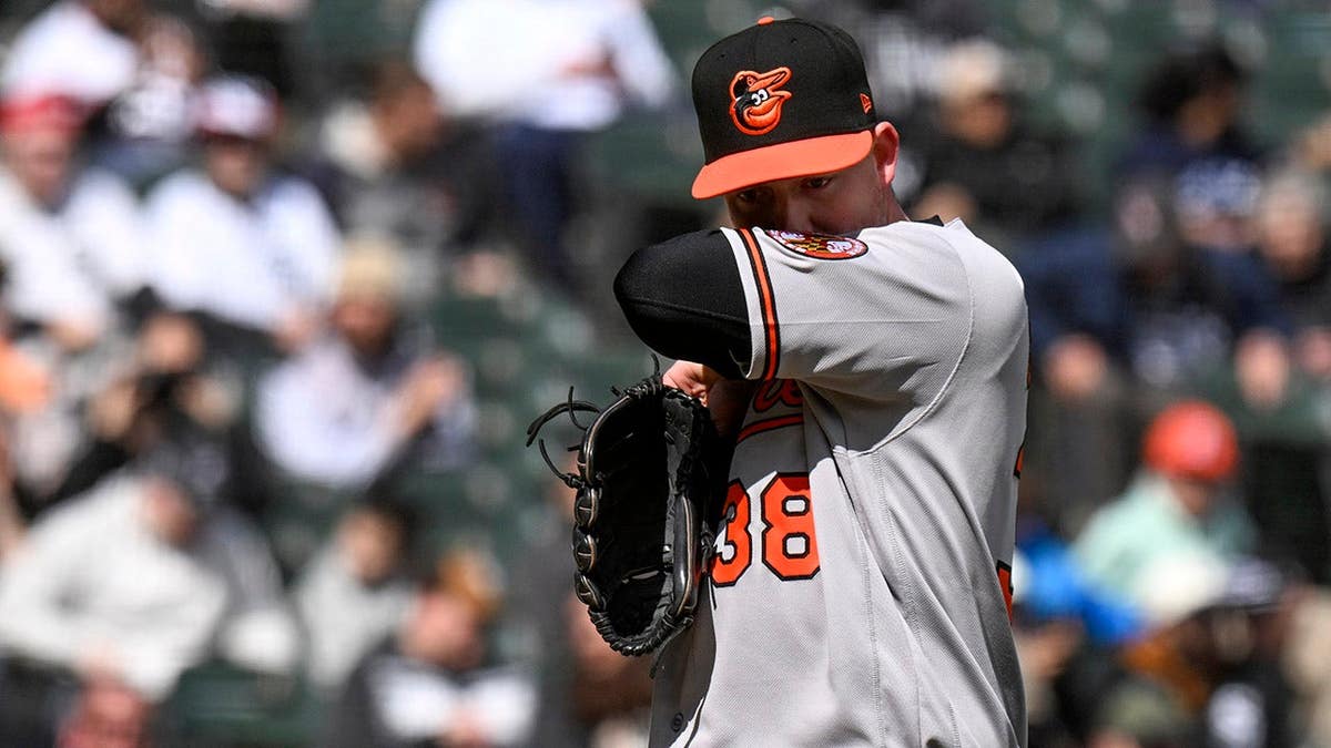 Baltimore Orioles pitcher Kyle Bradish wiping his face during a baseball game.