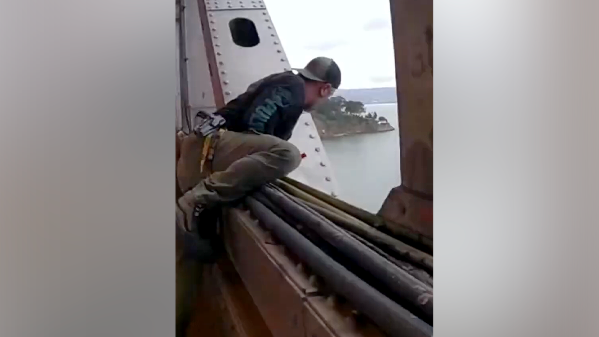 Officer looks over edge of Bay Bridge during police response to suspect underneath structure