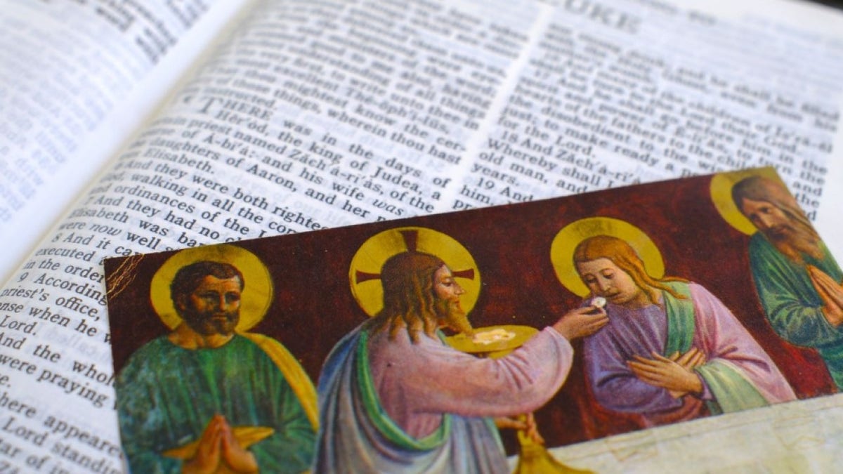 Jesus and the Apostles seated at the Last Supper with an open Bible showing a religious image.