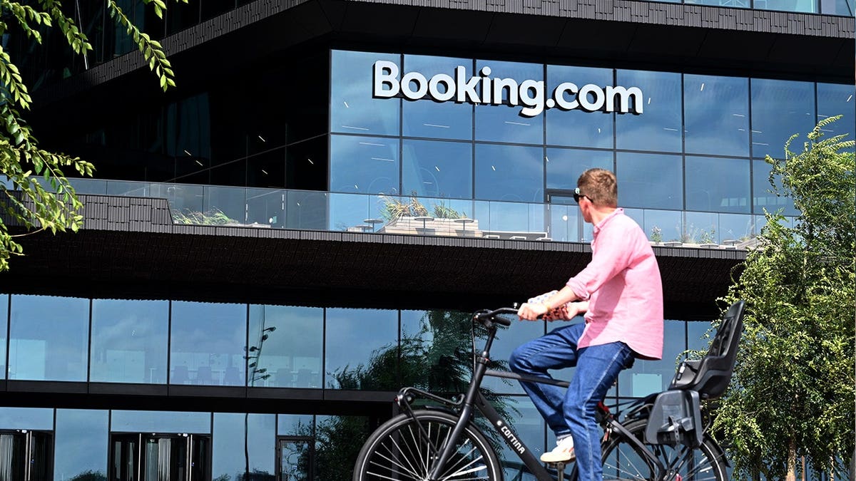 A man bikes past a Booking.com office.