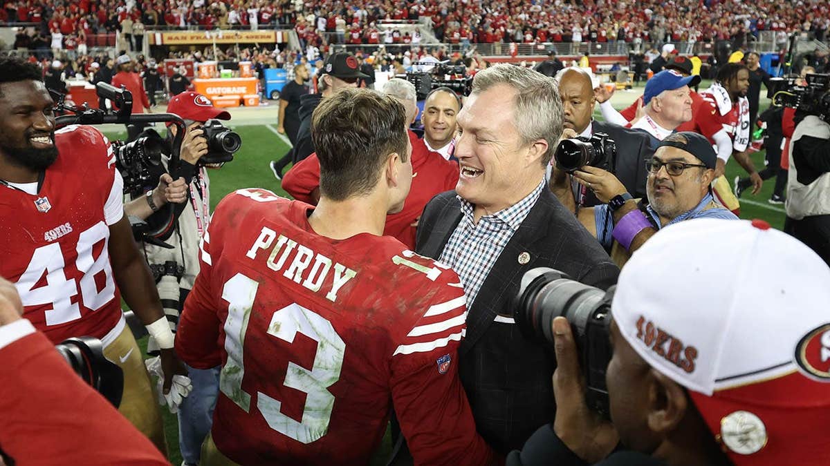 Brock Purdy celebrating with John Lynch on the field at Levi's Stadium