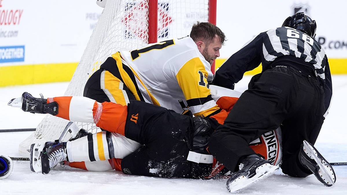 Pittsburgh Penguins' Bryan Rust wrestling Philadelphia Flyers' Travis Konecny on ice rink