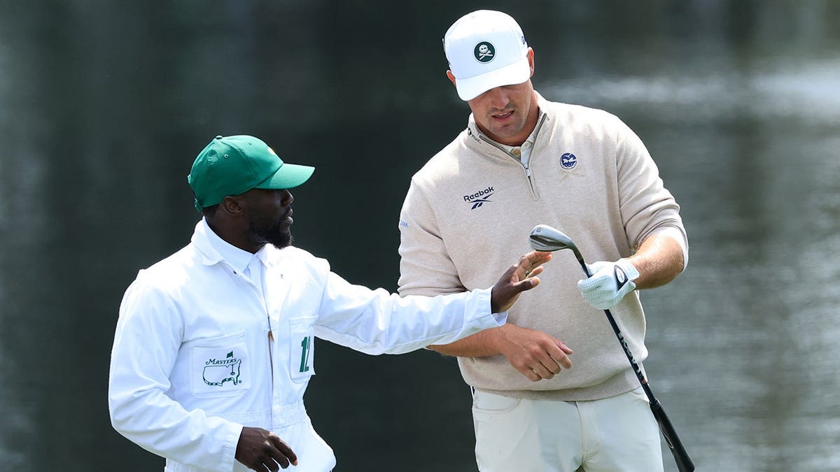 Bryson DeChambeau reacts with caddie Kevin Hart astatine  Augusta National Golf Club