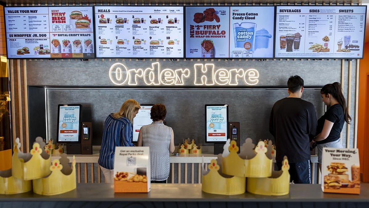 Customers using self-service ordering kiosks inside a Burger King restaurant in Hialeah, Florida