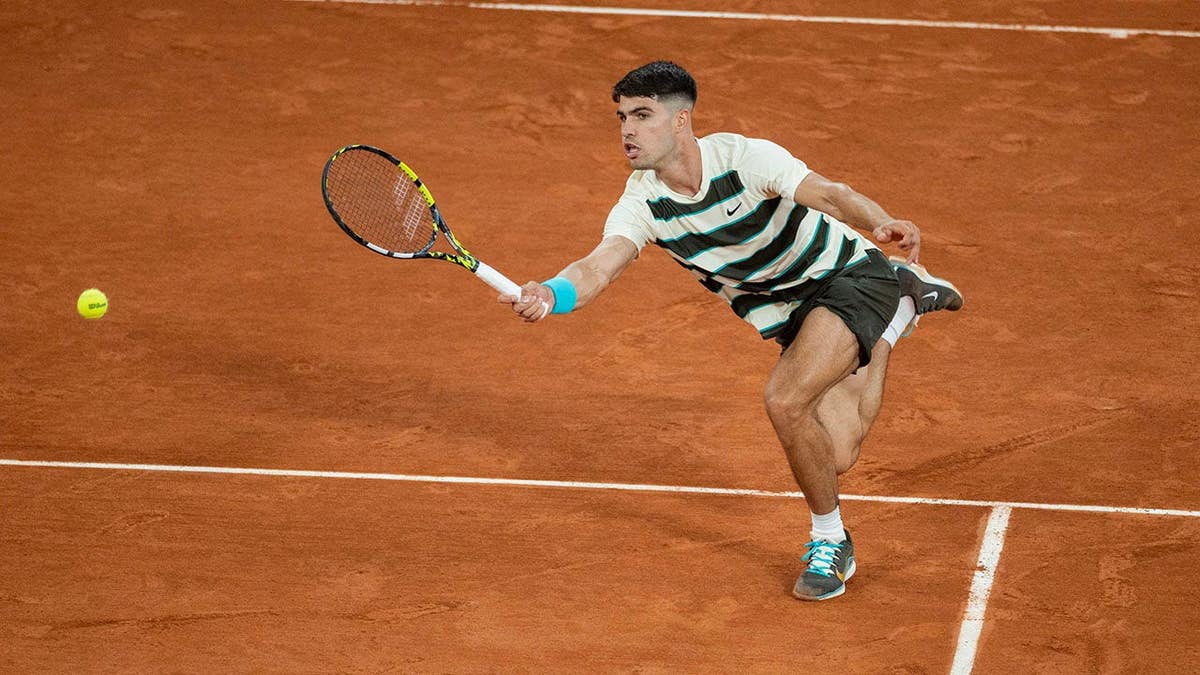 Carlos Alcaraz hitting a forehand during a tennis match at Roland Garros.