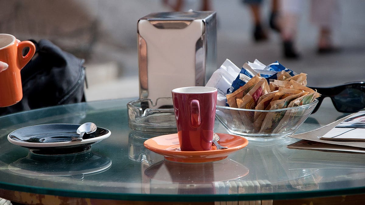 Coffee cup with sugar packets on a table
