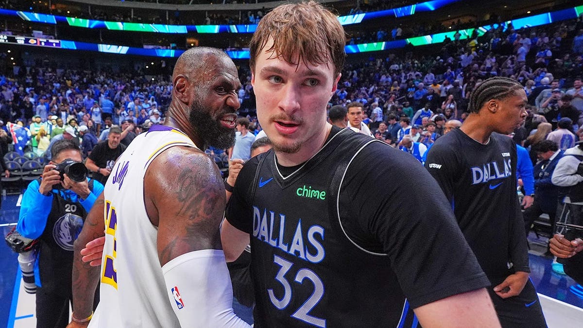 Dallas Mavericks forward Cooper Flagg hugging Los Angeles Lakers forward LeBron James on basketball court