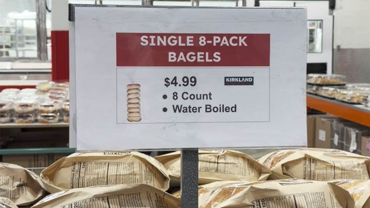 Sign advertising costco bagels in warehouse bakery section.