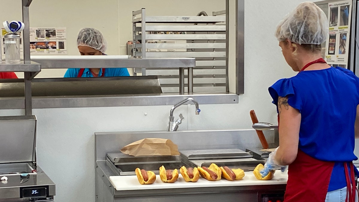 Employee preparing famous Costco Hot Dogs in kitchen, Costco store, Palm Beach, Florida.