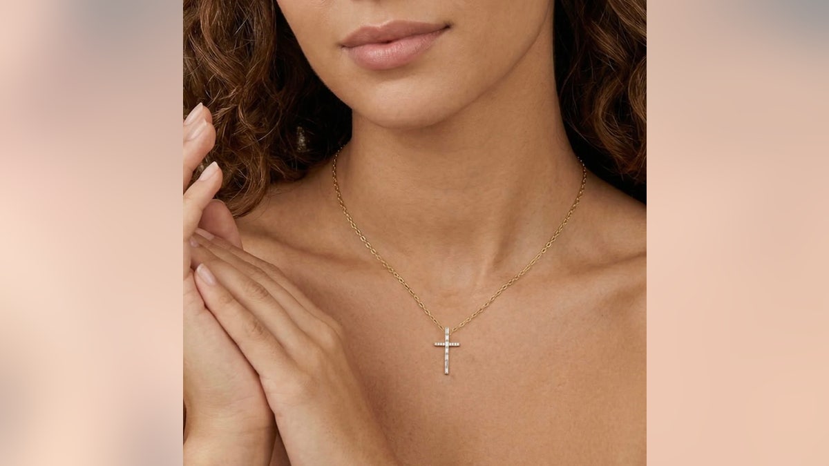 Esta cruz de ouro apresenta 15 diamantes em lapidação redonda e baguete.