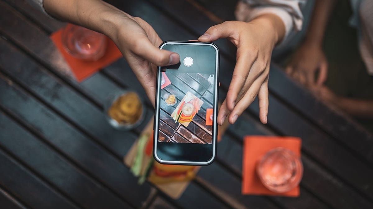 Clienti che fotografano cibi vivaci con gli smartphone mentre cenano in un ristorante