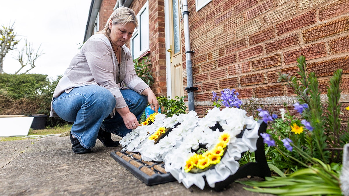 Dawn Turner squatting down and looking at flowers for her son Rob.