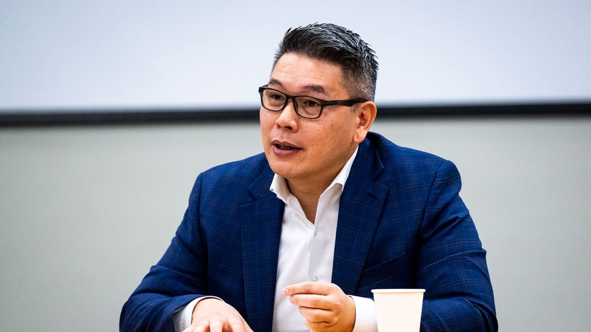 Derek Tran wears glasses and talks in a suit