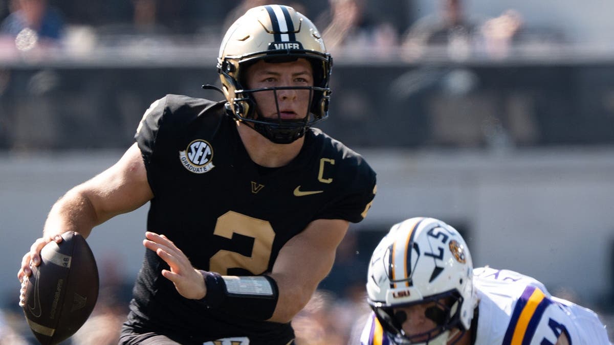 Vanderbilt quarterback Diego Pavia running with the football on a field.