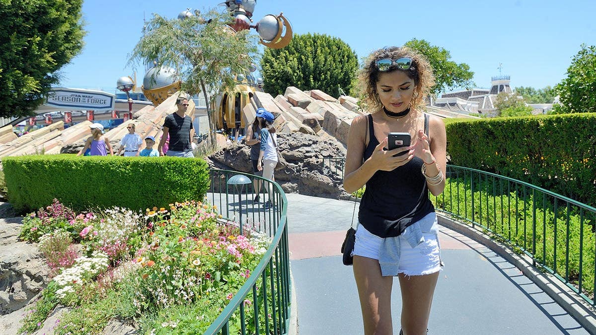 Michelle Mendez walking retired  of Tomorrowland playing Pokemon Go astatine  Disneyland
