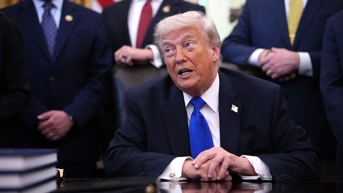 President Donald Trump sitting at his desk in the Oval Office