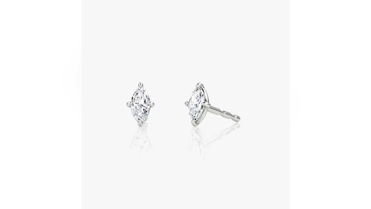 Um par de tachas em forma de diamante se destaca em comparação aos brincos redondos tradicionais.