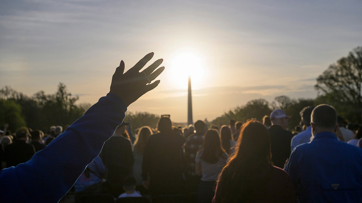People raising hands during Easter Sunday sunrise prayer at Lincoln Memorial in Washington