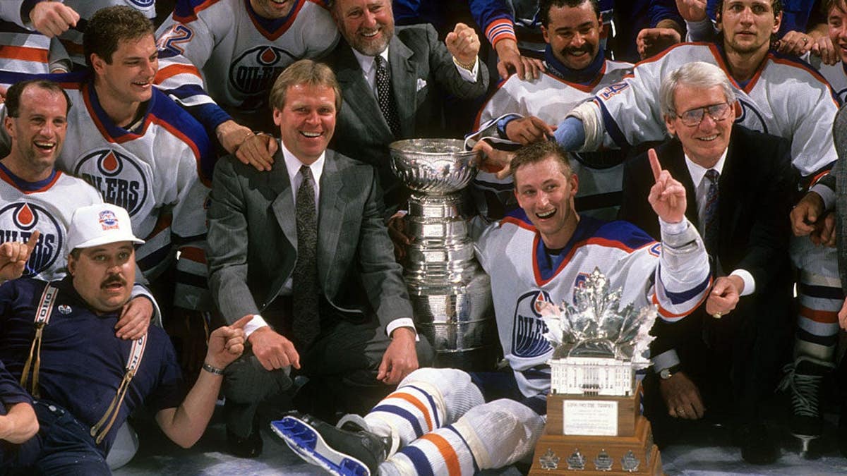 Wayne Gretzky and Edmonton Oilers team holding Stanley Cup and Conn Smythe Trophy