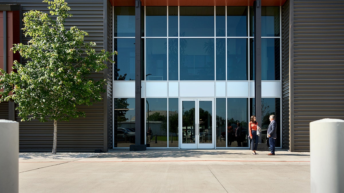 Two people talk outside of an office building.