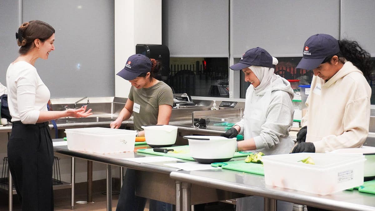 Eliza can be seen instructing three students from Tufts Medical, Dental, and Friedman School of Nutrition during the cooking portion of class.