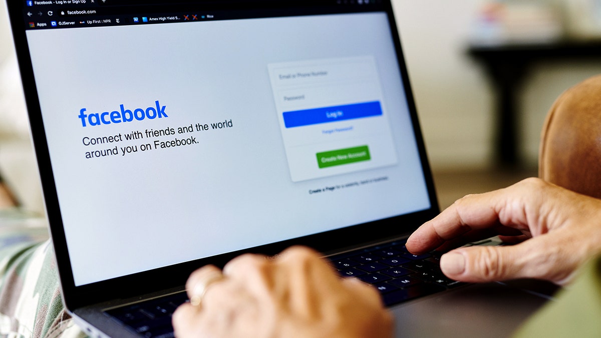 A person accesses Facebook on a laptop.