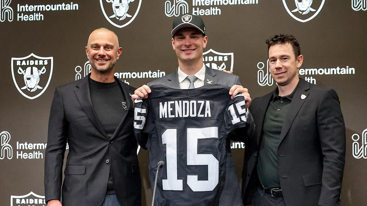 Quarterback Fernando Mendoza posing with Raiders general manager John Spytek and head coach Klint Kubiak at a news conference