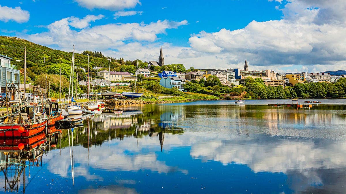 Pier at the port of Clifden with boats anchored and reflections in the water