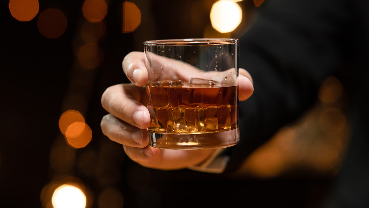 Hand holding glass of whiskey.