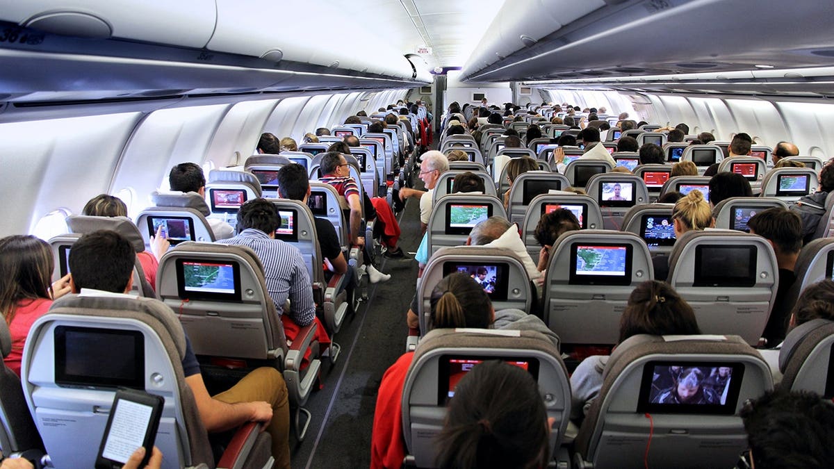 Passengers seated inside an Iberia Airbus A340 aircraft cabin.