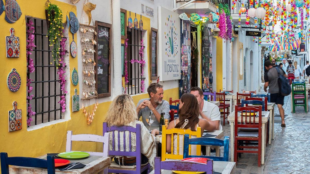 Majorca, Menorca and Ibiza want to cap visitor numbers as overtourism surges 2 People sitting at a table in a small cozy restaurant in Ibiza Town